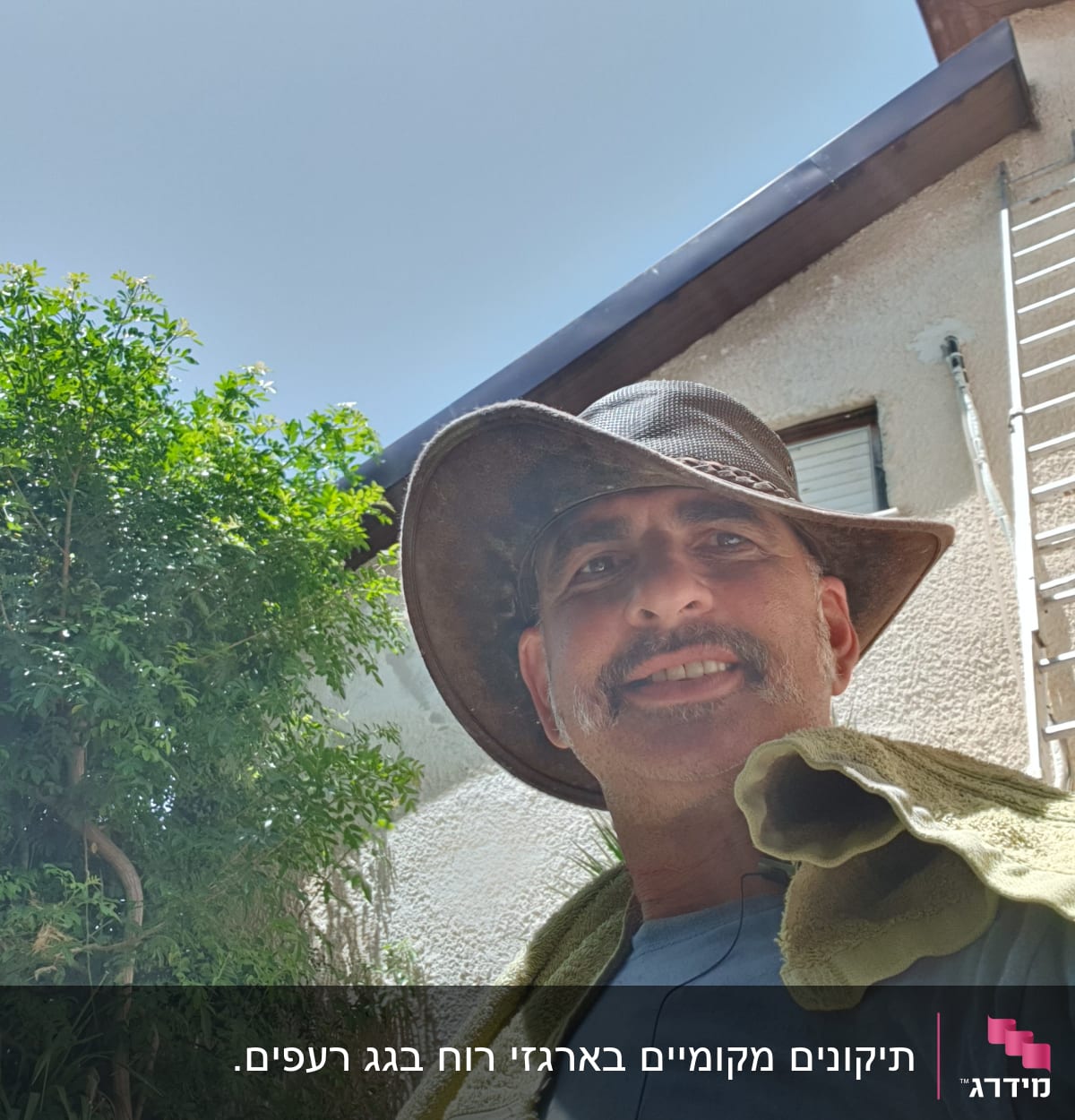 סולם מתכת נשען על קיר ליד גג הבית